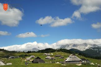 Pogled na pastirsko naselje Veliki stan na Veliki planini. V ozadju Planjava v oblakih. Foto: Anja Jerin, 2016. 